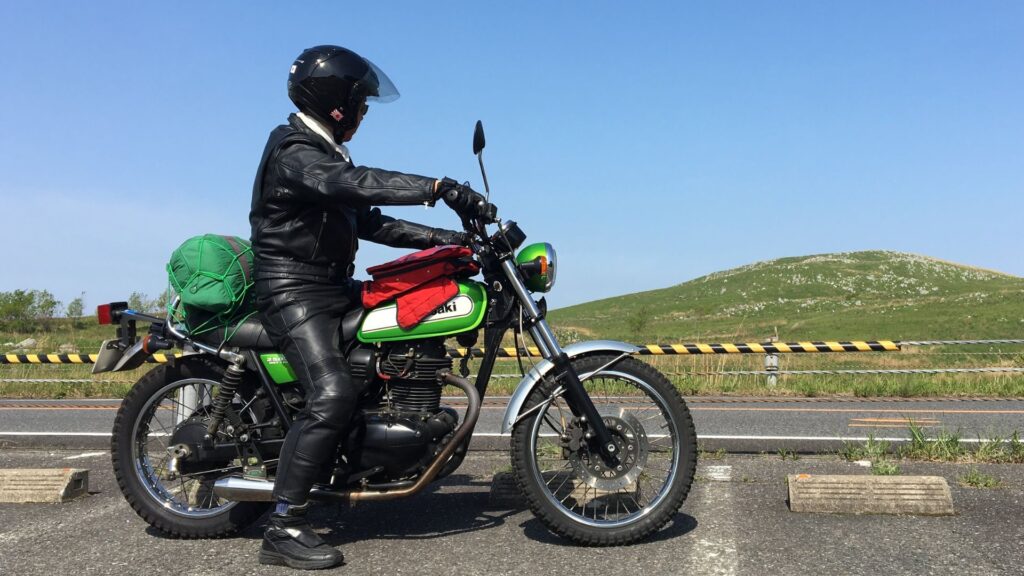 ロングツーリングしている筆者の画像。バイクに乗り、美しい日本の山眺めている姿を横から撮影している。