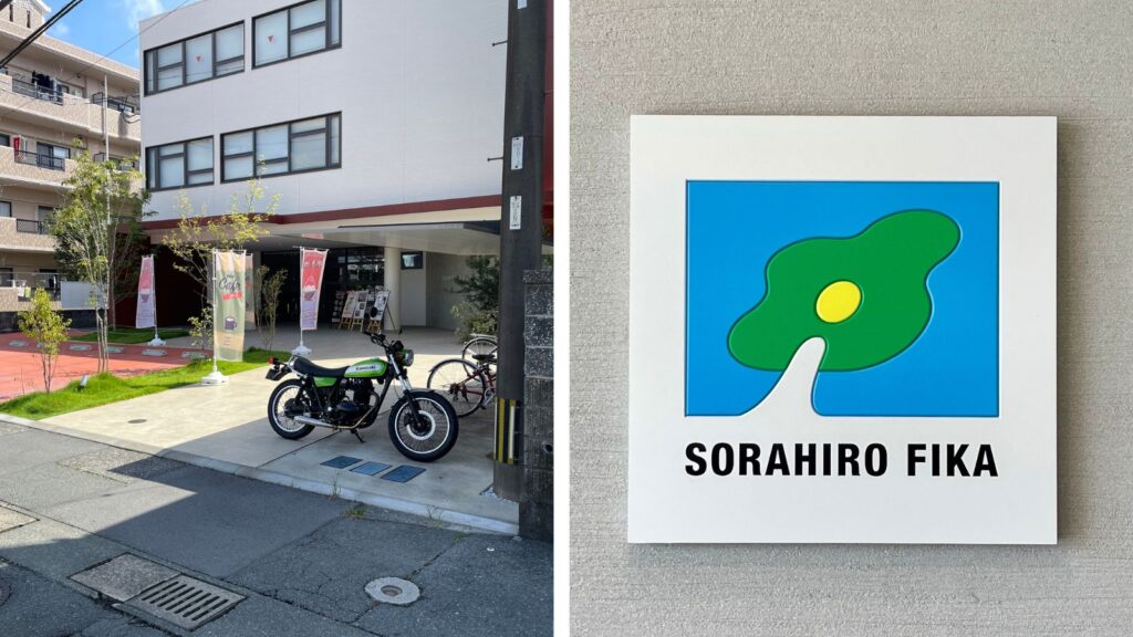 熊本のカフェ「SORAHIRO FIKA」の店舗前に停められた筆者のバイクと、お店のスタイリッシュなロゴの看板を組み合わせた写真。