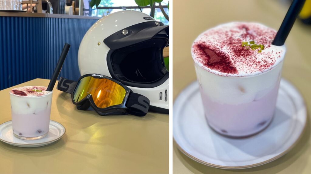 バイクのヘルメットの横に置かれた、SORAHIRO FIKAの特製スイーツドリンク。紫色のドリンクと白いフォームの層が美しい。