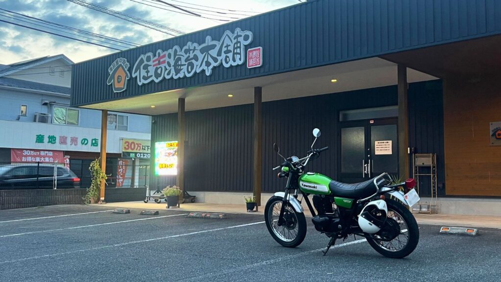 熊本県宇土市にある住吉海苔本舗の広い駐車場に停車したカワサキ250TR。バイクツーリングの立ち寄りスポットとして安心して利用できる店舗外観。