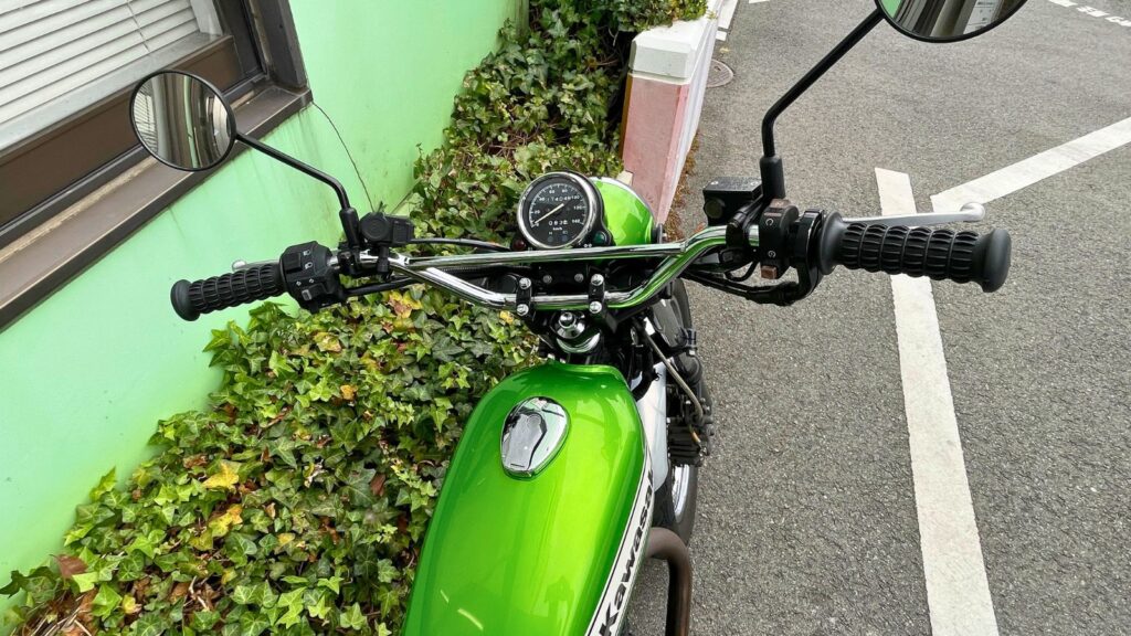 カワサキ250TRの運転席(コックピット)視点の画像。交換した樽型グリップのレトロな形状が、キャンディライムグリーンのタンクやメッキパーツとマッチし、クラシックな雰囲気を高めている様子。