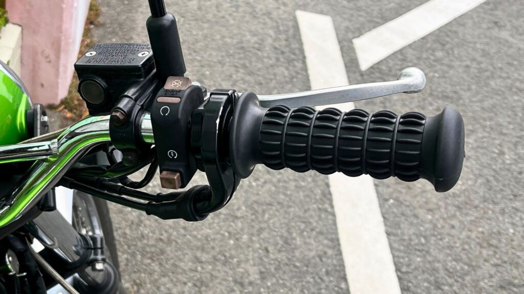 カワサキ250TRに装着した樽型グリップの拡大画像。肉厚な太さと表面のヒダ(リブ)が手のひらにフィットし、握力を使わずにアクセル操作ができる様子。