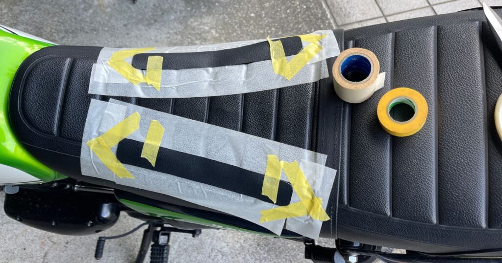 250TRのシートに補修用合皮を仮置きし、周囲をマスキングテープで囲って接着範囲を決めた様子。