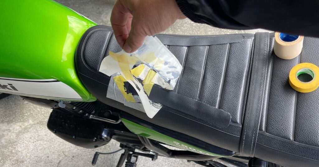 バイクシートのリペア後に、周囲の養生に使用したマスキングテープを丁寧に剥がす工程。