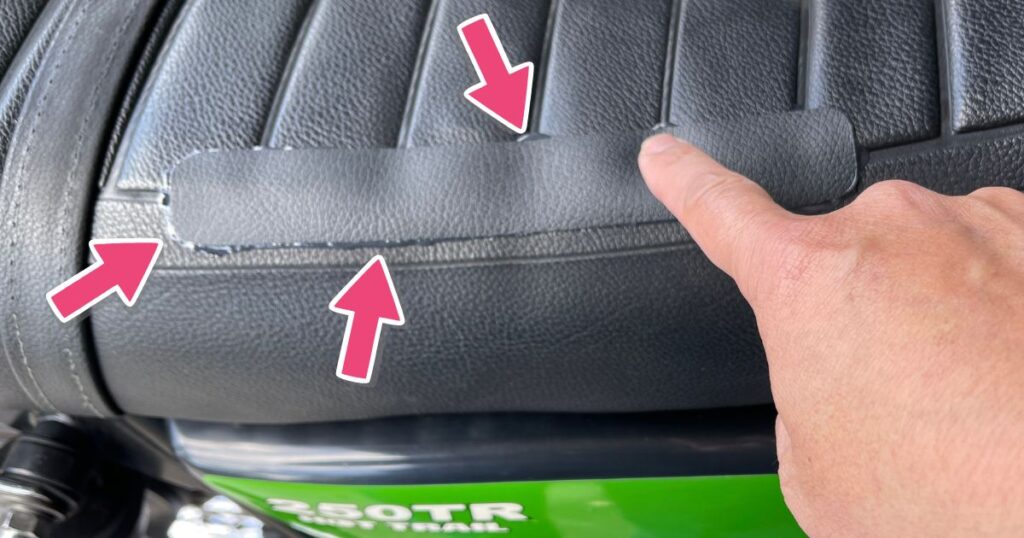 バイクシートの補修パッチを指で押し、接着剤をあえてはみ出させてエッジを封じ込める様子。